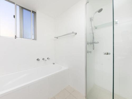 un bagno bianco con vasca e doccia in vetro di Beachpoint G2 a Forster