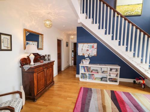 a living room with a staircase and a book shelf at Millers Lane House in Aught Upper