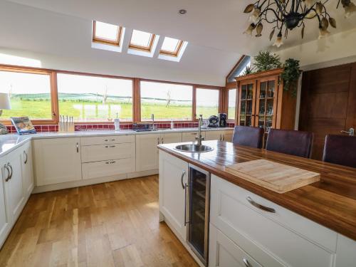 a kitchen with white cabinets and a large window at Millers Lane House in Aught Upper