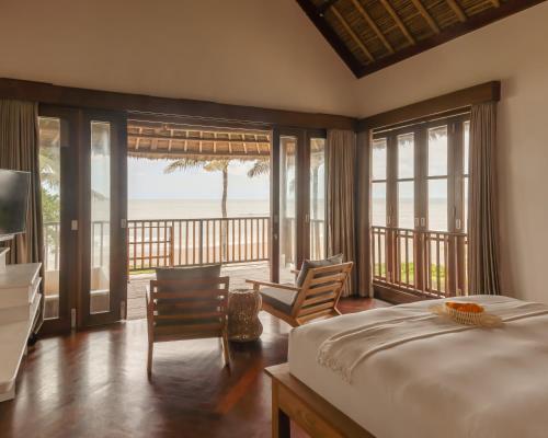 a bedroom with a bed and a view of the ocean at Sound of The Sea Villa in Canggu