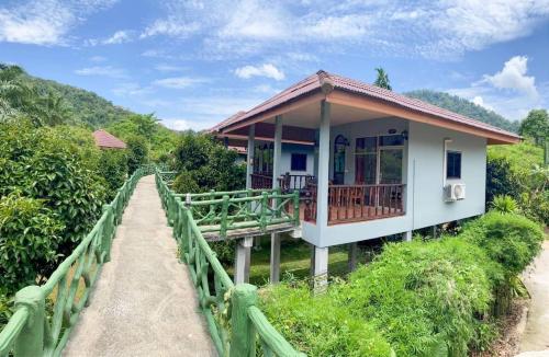 a house on a bridge with a walkway to it at Khao Sok Jungle Huts Resort in Khao Sok National Park