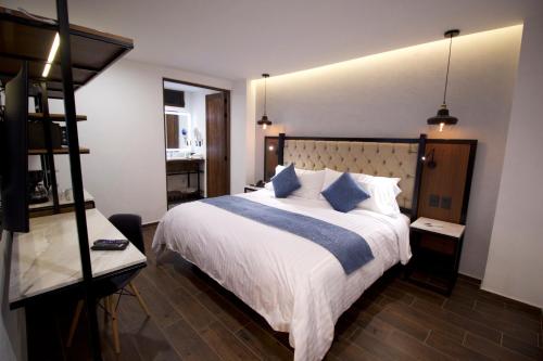 a bedroom with a large white bed with blue pillows at Hotel Boutique Casa Loreta in Querétaro