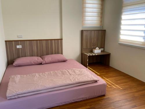 a bed with pink sheets and a wooden headboard in a bedroom at Shiny Homestay in Magong