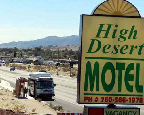 a sign for a high desert motel with a bus at High Desert Motel Joshua Tree National Park in Joshua Tree
