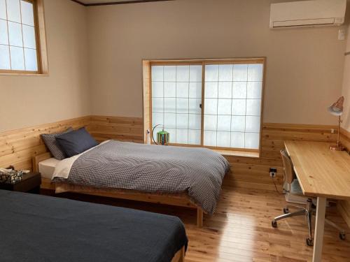 a bedroom with a bed and a desk and a window at Marushige in Nozawa Onsen