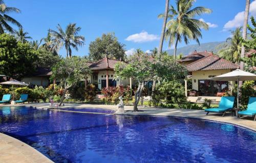 a swimming pool in front of a house with palm trees at Holiway Garden Resort & SPA - Bali - CHSE Certified Hotel in Tejakula