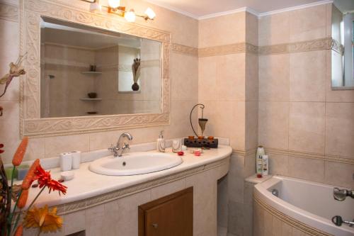 een badkamer met een wastafel, een bad en een spiegel bij Castel View Experience in Kissamos