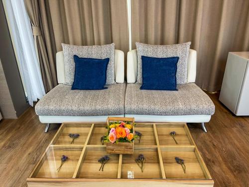 a couch with blue pillows and a tray with flowers on it at Treescape Resort Chiangmai in Chiang Mai