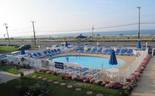 a pool with chairs and umbrellas in a parking lot at Colton Court Motor Inn in Cape May