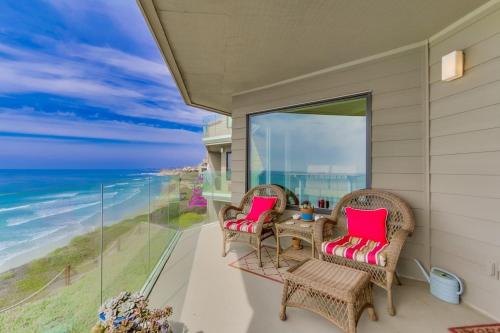 a balcony with chairs and a table with a view of the ocean at Work Friendly Oceanfront SURF25 Condo in Solana Beach