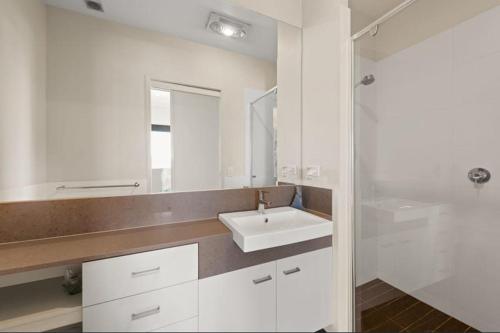 a white bathroom with a sink and a mirror at Keith's on Pumicestone, 1 of the 3 most popular units on Bribie in Bongaree
