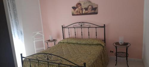 1 dormitorio con 1 cama, 2 mesas y una foto en la pared en Casa Sarahouse, en Taranto