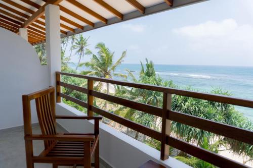 a room with a balcony with a chair and the ocean at La Polena in Matara