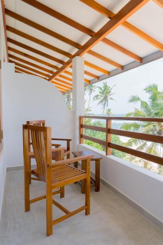 a porch with a wooden bench and a table at La Polena in Matara