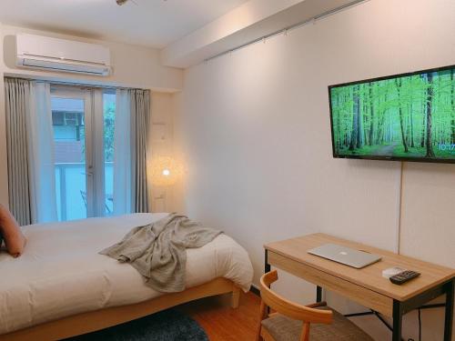 a bedroom with a bed and a table and a television at Dash Living Shinjuku in Tokyo