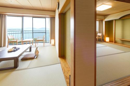 a room with a balcony with a table and chairs at KAMENOI HOTEL Genkainada in Kitakyushu