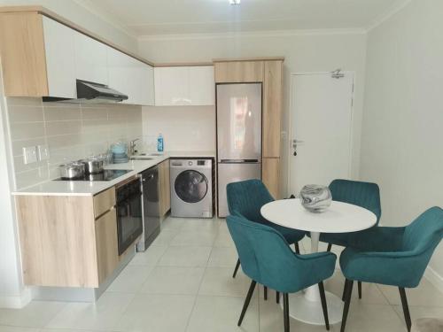 a kitchen with a table and blue chairs in a kitchen at The Blyde apartment NO BRAAI OR PARTY in Pretoria