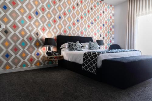 a bedroom with a bed and a patterned wall at Hallmark House Hotel in Johannesburg