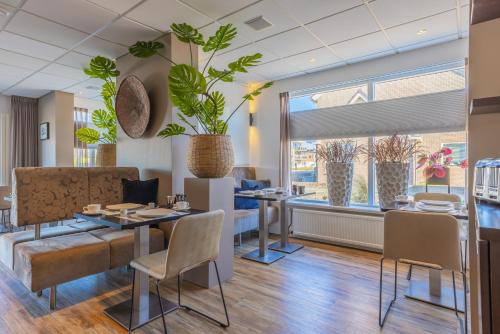 a restaurant with a table and chairs and plants at Hotel De Koningshof in Noordwijk aan Zee