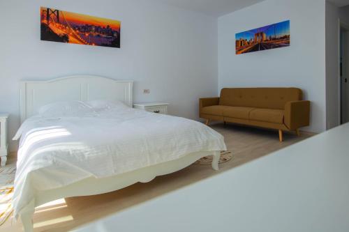 een witte slaapkamer met een bed en een bank bij Derby Beach Mamaia. in Mamaia