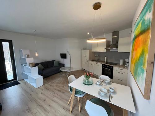 eine Küche und ein Wohnzimmer mit einem weißen Tisch und Stühlen in der Unterkunft Moderne Ferienwohnung zum Wohlfühlen in Lindenberg im Allgäu