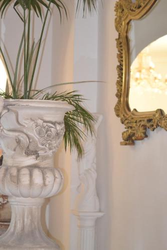 a white vase with a plant in it next to a mirror at Villa Ambra B&B in Noto