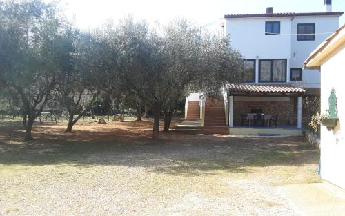 a house with a porch and trees in front of it at Apartments Nena 3* in Ližnjan