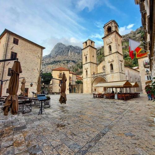 a courtyard with an old building and a castle at Old town Kotor Square in Kotor