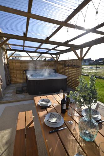 une terrasse avec une table en bois et un bain à remous dans l'établissement La Bulle Emeraude, détente à deux, en famille ou entre amis, à Plancoët