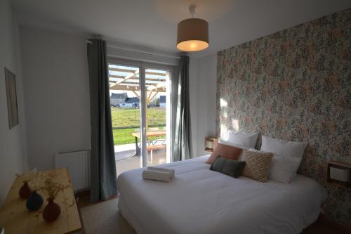 ein Schlafzimmer mit einem großen weißen Bett mit einem Fenster in der Unterkunft La Bulle Emeraude, détente à deux, en famille ou entre amis in Plancoët