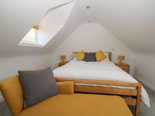 a bedroom with a bed and a yellow couch at Broadford Barn - Barn conversion in picturesque village in Shalford