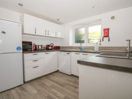 a kitchen with white cabinets and a white refrigerator at Broadford Barn - Barn conversion in picturesque village in Shalford