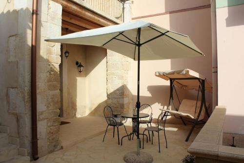 een tafel en stoelen onder een parasol op een patio bij Flower house in Noto
