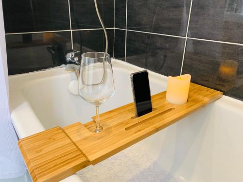 - un verre de vin et un téléphone portable sur un plateau en bois dans une baignoire dans l'établissement Nice cocooning apartment for a relaxing moment, à Reims