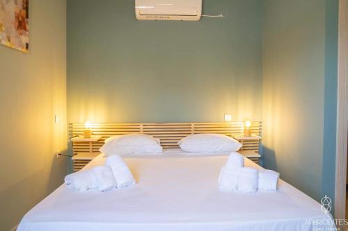 1 dormitorio con 1 cama con sábanas y almohadas blancas en Aphrodite’s Cozy House, en Kolimvárion