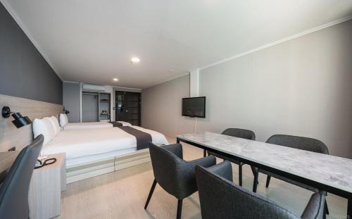 a hotel room with a bed and a table and chairs at Gyeongpo Soo Hotel in Gangneung