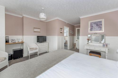 a bedroom with a large white bed and a tv at Exmoor House in Wheddon Cross