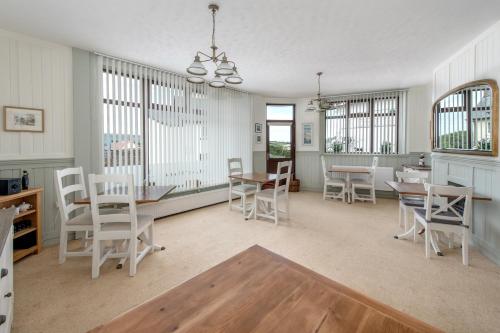 a dining room with white chairs and a table at Exmoor House in Wheddon Cross
