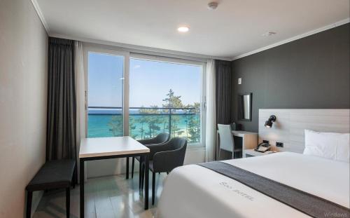 a hotel room with a bed and a desk and a window at Gyeongpo Soo Hotel in Gangneung