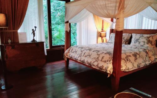 a bedroom with a canopy bed and a window at Mi Casa - The gem of Ijen in Banyuwangi