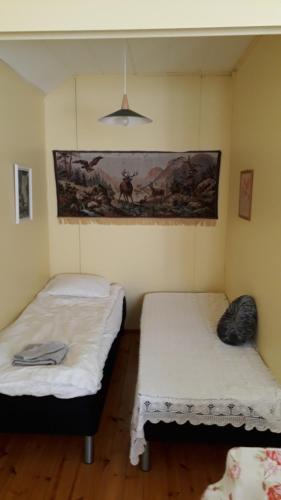 two beds in a room with a painting on the wall at Studio mummola in Varkaus