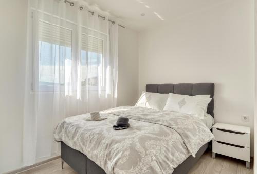 a white bedroom with a bed and a window at Apartment La Perla in Đenovići