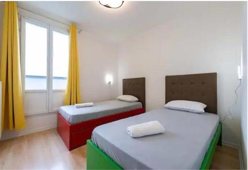 Duas camas num pequeno quarto com uma janela em VERY CENTRAL DISNEYLAND apartment em Serris