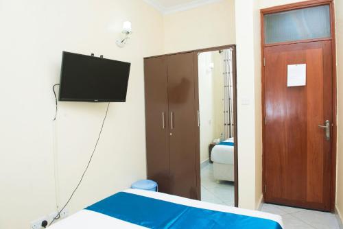 Habitación con cama y TV en la pared. en Airport Transit Lodges en Dar es Salaam