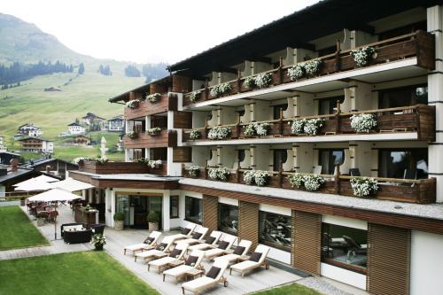 a large building with chairs and a patio at Hotel Berghof in Lech am Arlberg