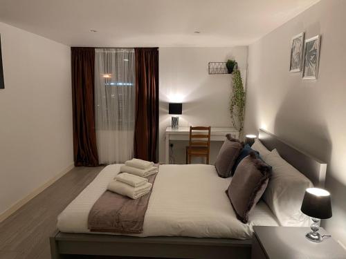 a bedroom with a large bed with a desk and a window at City airport serviced apartment London in London