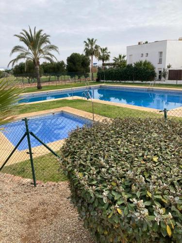 a swimming pool with a hedge next to a fence at Apartamento El Toyo in Almería