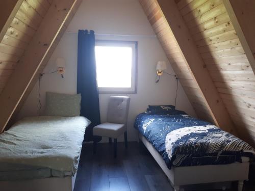 a bedroom with a bed and a chair and a window at A-frame volledig vrijstaande woning in Hensbroek