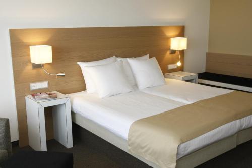 - une chambre avec un grand lit blanc et deux lampes dans l'établissement WestCord Hotel Schylge, à West-Terschelling