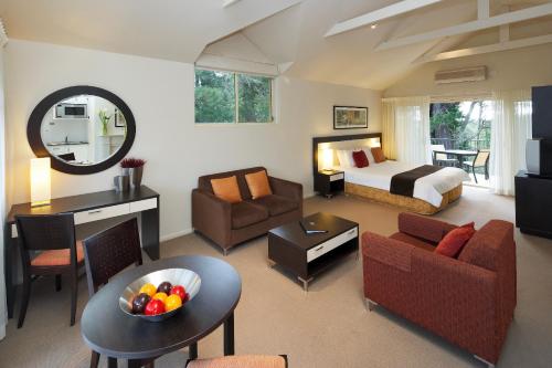 Habitación de hotel con cama y sala de estar. en Falls Mountain Retreat Blue Mountains, en Wentworth Falls